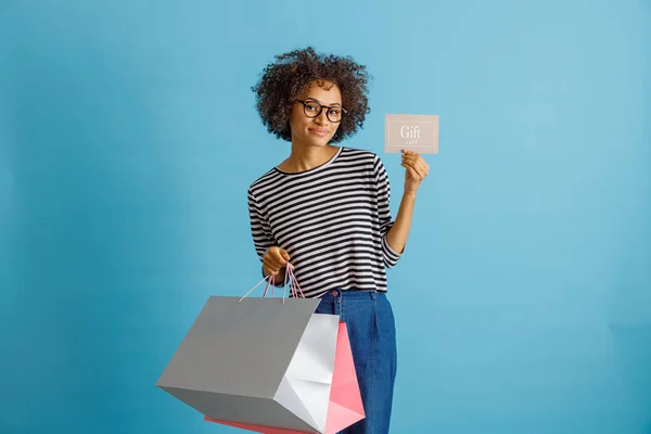 Mujer africana alegre sosteniendo compras y tarjeta de regalo —  Fotos de Stock