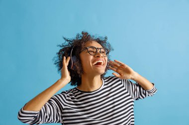 Kablosuz kulaklıkla müzik dinleyen mutlu bir kadın.