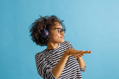 Kulaklıklı genç bir kadın stüdyoda müzik dinliyor.