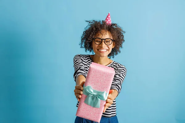Glada kvinna i födelsedagskon hatt innehav present — Stockfoto
