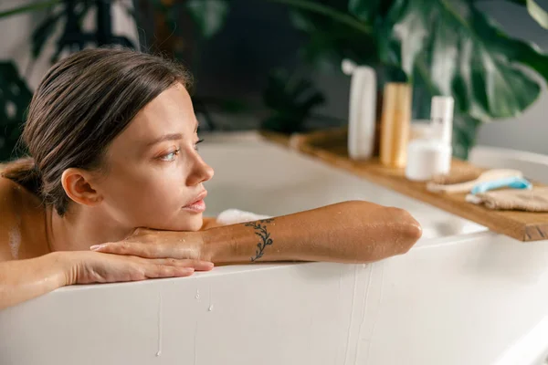 高級スパリゾートで浴槽でリラックスしながら脇を見てかなり若い女性のクローズアップ肖像画 — ストック写真