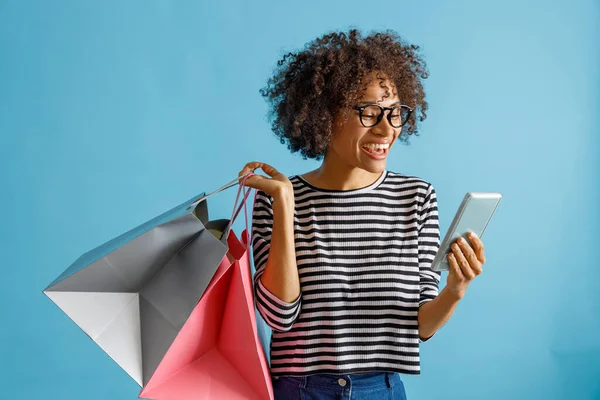 Mujer alegre con bolsas de compras utilizando el teléfono móvil —  Fotos de Stock