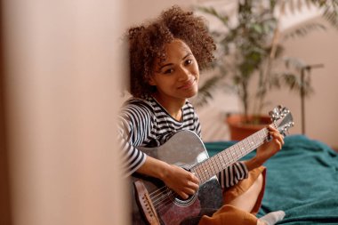 Kadın gitarist evde gitar çalıyor.