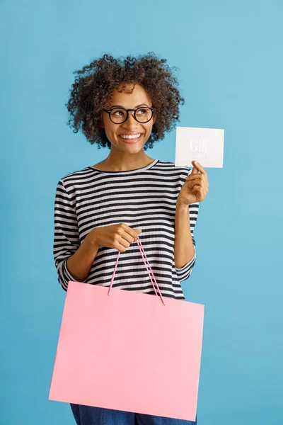 Mujer alegre sosteniendo bolsa de compras y tarjeta de regalo —  Fotos de Stock