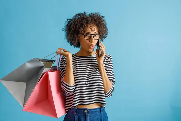 Verblüffte Frau mit Einkaufstasche telefoniert — Stockfoto