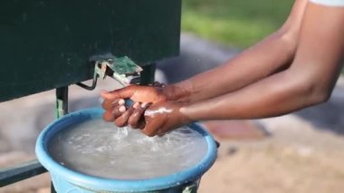 Afrikalı bir adam ellerini dışarıda yıkıyor.