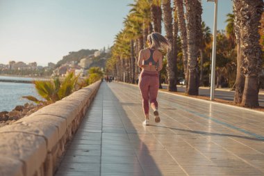 Rıhtımda aktif olarak koşan atletik güzel kadın.