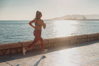 Rıhtımda aktif olarak koşan atletik güzel kadın.