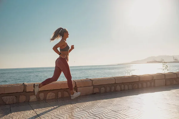 Deportiva dama corriendo activamente por el paseo marítimo —  Fotos de Stock