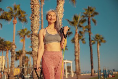 Spor giyimli kadın portresi. Forma dirençli bantlarla egzersiz yapıyor.