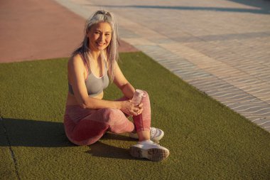 Gülümseyen kadın sahilde iyi bir antrenmandan sonra dinleniyor.