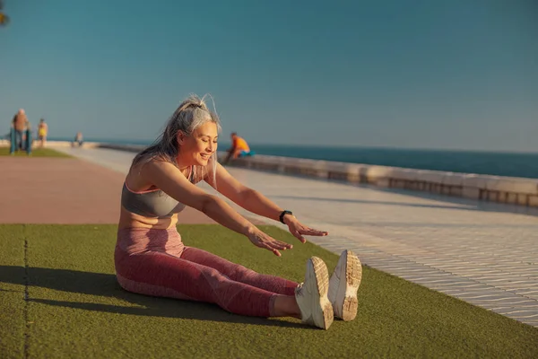 Entrenamiento femenino fuerte feliz en el día soleado en la orilla del mar —  Fotos de Stock