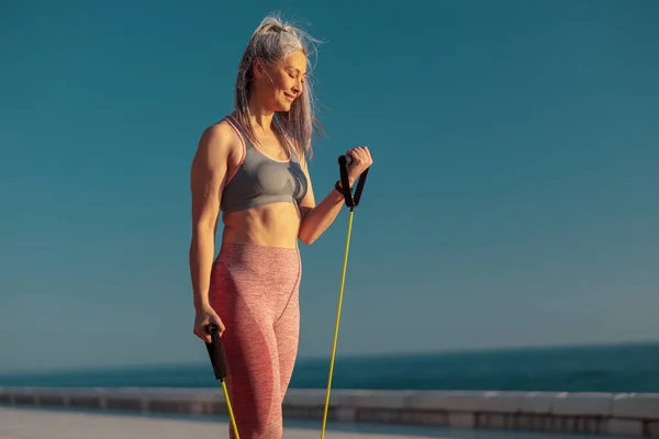 Mujer fuerte en ropa deportiva haciendo ejercicio en el sitio de deportes, utilizando bandas de resistencia de fitness —  Fotos de Stock