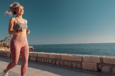 Atletik mutlu kadın limanda aktif olarak antrenman yapıyor.