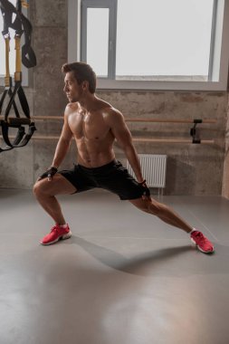 Gömleksiz sporcu spor salonunda hamle yapıyor.