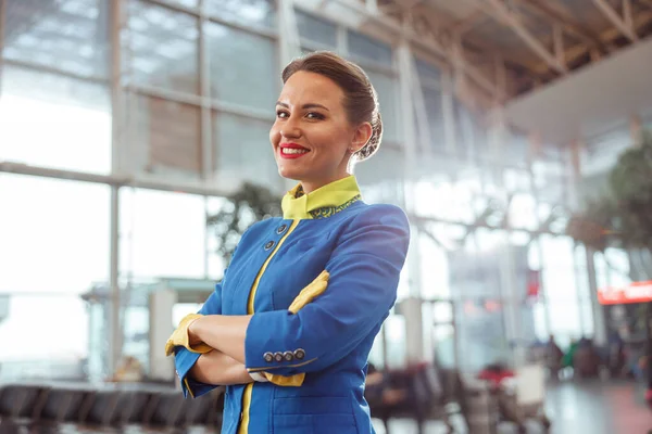 Wesoła kobieta pracownik linii lotniczych stojących w terminalu lotniska — Zdjęcie stockowe