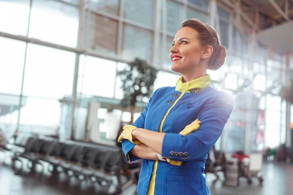 Χαρούμενη γυναίκα αεροσυνοδός στέκεται στο αεροδρόμιο τερματικό — Φωτογραφία Αρχείου