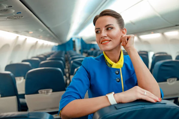 Alegre azafata mujer de pie en el salón de pasajeros del avión —  Fotos de Stock
