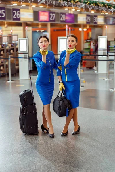 Dvě ženy letušky foukání polibek na letišti terminálu — Stock fotografie