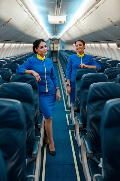 Assistenti di volo donne in piedi in cabina passeggeri di aeromobili — Foto Stock