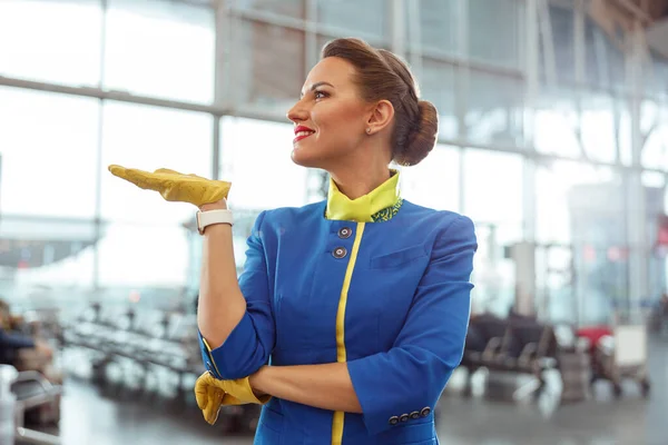 Alegre azafata femenina de pie en la terminal del aeropuerto — Foto de Stock