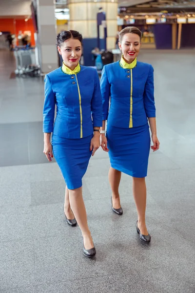 Veselé ženy letušky kráčející po letišti terminálu — Stock fotografie