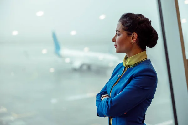 Female flight attendant looking out the window in airport terminal — Stock Photo, Image