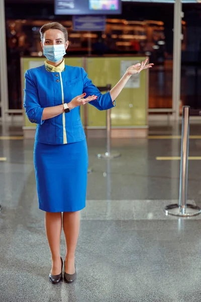 공항으로 초대하는 의료용 마스크를 쓴 스튜어디스 — 스톡 사진