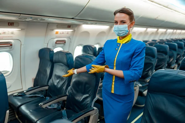 Letuška v masce zve na sedadlo spolujezdce v letadle — Stock fotografie
