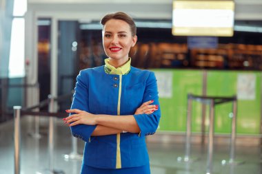 Neşeli kadın hostes havaalanı terminalinde duruyor.
