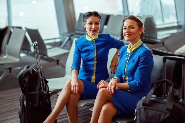 Donne gioiose hostess in attesa del volo in aeroporto — Foto Stock