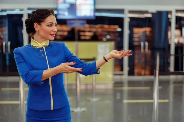Assistente di volo donna che dà il benvenuto al volo in aeroporto — Foto Stock