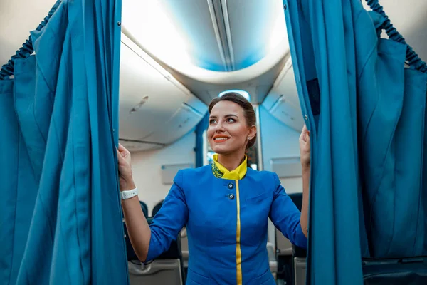 Donna hostess gioiosa che tiene tende in aereo passeggero — Foto Stock