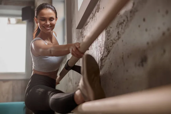 Mujer sonriente haciendo estiramiento en el gimnasio —  Fotos de Stock