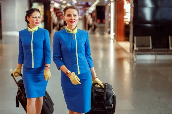 Assistenti di volo donne che trasportano borse di viaggio in aeroporto — Foto Stock
