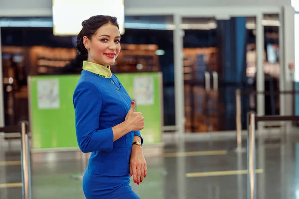 Wesoła stewardessa okazuje gest aprobaty na lotnisku — Zdjęcie stockowe