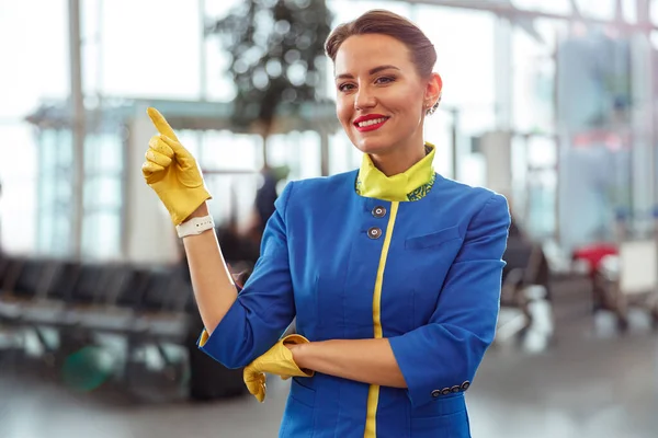 Cheerful stewardess pointing at something in airport terminal — Stock Photo, Image