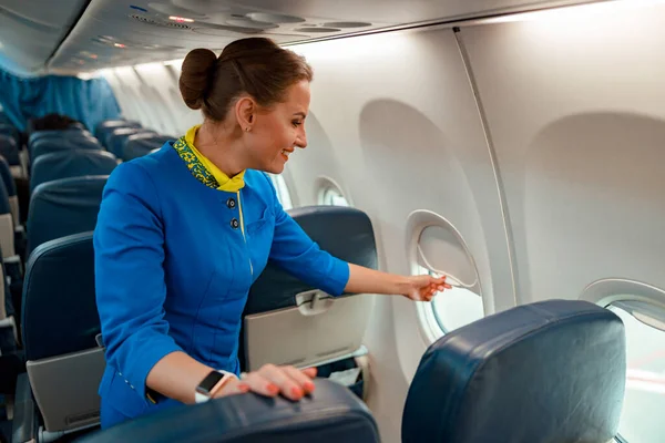 Donna sorridente hostess finestra di chiusura in aereo — Foto Stock