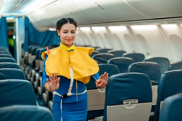 Flight attendant demonstrating how to use life vest in airplane — Foto Stock