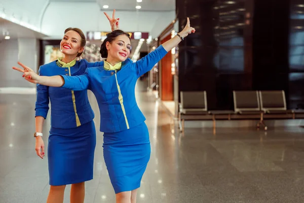 Donne allegre hostess mostrando gesto vittoria in aeroporto — Foto Stock