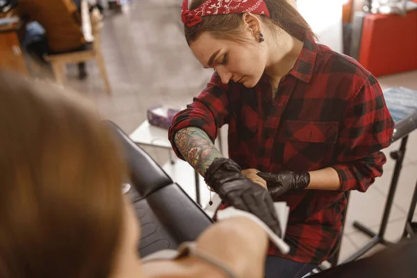 Focused woman tattoo master treating client skin — Stock Photo, Image