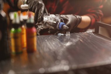 Dövme ustası plastik kavanoza siyah boya döküyor.