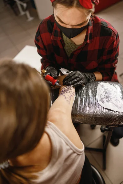 Vertical photo of tattoo artist inking tattoo on forearm — Stock Photo, Image