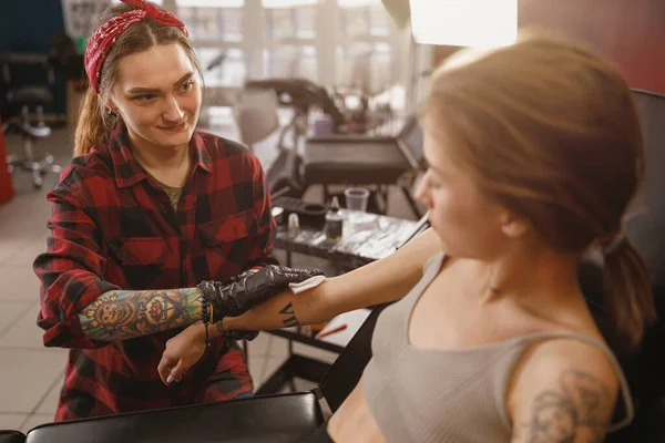 Young tattoo master wiping client hand with alcohol wipe — Stock Photo, Image