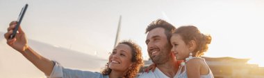 Mutlu turistler, güzel bir aile, gün batımında uçağa binmek için dışarıda beklerken selfie çekiyorlar.