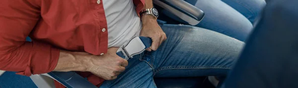 Vista de ángulo alto del cinturón de seguridad de los pasajeros masculinos mientras están sentados en el avión para un vuelo seguro — Foto de Stock
