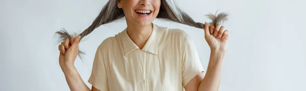 Gelukkig middelbare leeftijd aziatische vrouw houdt gedraaide taille haar op licht grijs achtergrond — Stockfoto