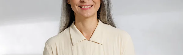 Portret van mooie grijsharige vrouw in beige blouse op lichte achtergrond — Stockfoto