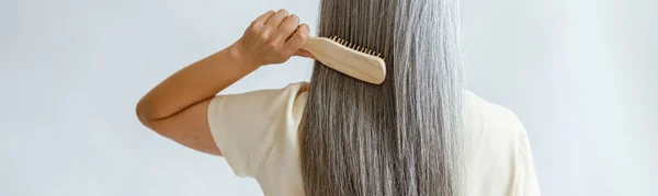 Lady kefék egyenes ezüst haj álló világos szürke háttér — Stock Fotó