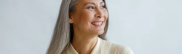 Joyful lmiddle aged dame dragen beige blouse staat op lichte achtergrond — Stockfoto